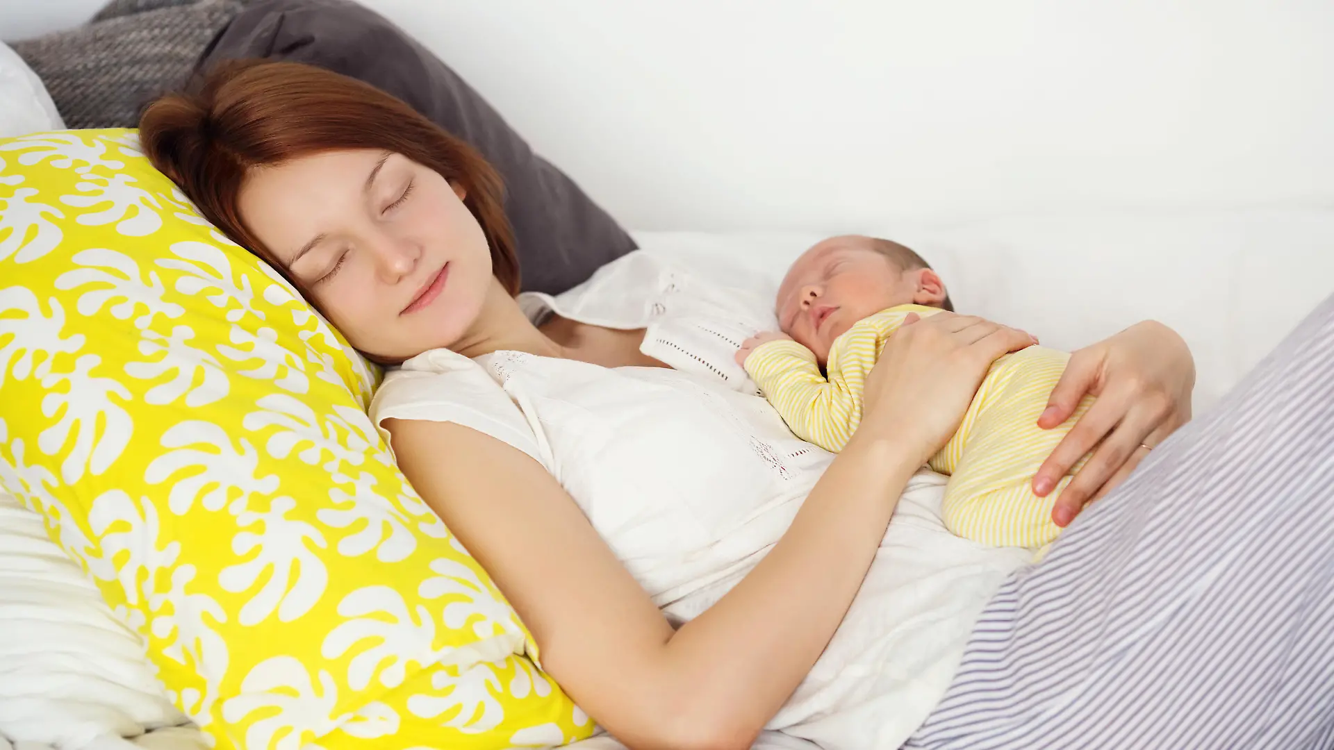 Mutter schläft mit Baby im Arm