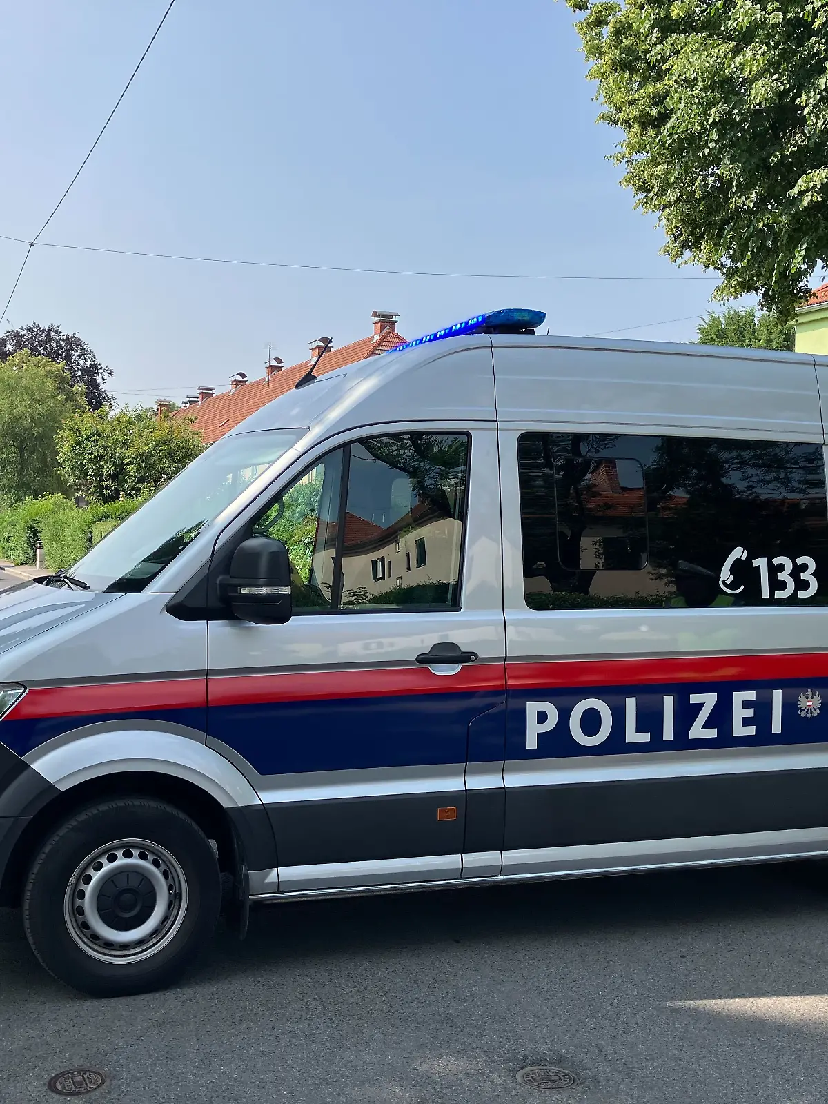 Ein Polizeiwagen blockiert eine Straße. Die Polizei in Graz (Österreich) hat die Zufahrt zu einem Kindergarten abgesperrt. Dort wurde ein verdächtiger Gegenstand gefunden.