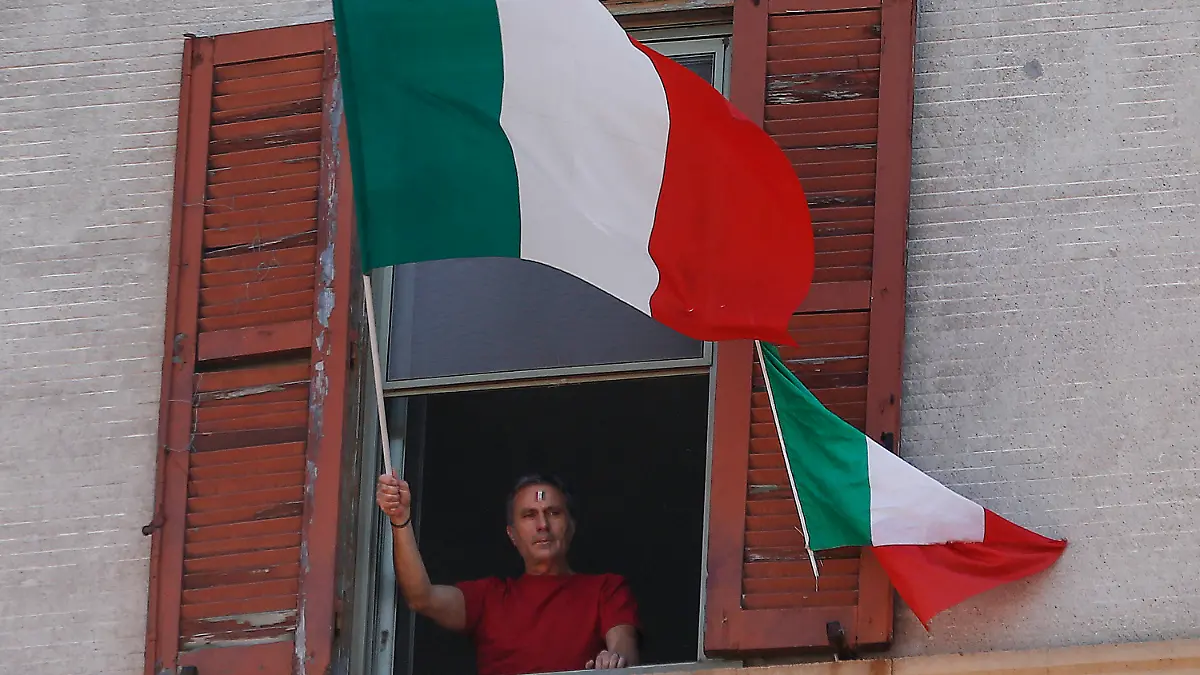 25.04.2020, Italien, Rom: Ein Mann schwenkt am Tag der Befreiung Italiens von seiner Wohnungen aus die italienische Fahne. Die üblichen Märsche in Gedenken an die Befreiung von den Deutschen Besatzern im Zweiten Weltkrieg, können während der Corona-Pandemie nicht stattfinden. Foto: Cecilia Fabiano/LaPresse via ZUMA Press/dpa +++ dpa-Bildfunk +++