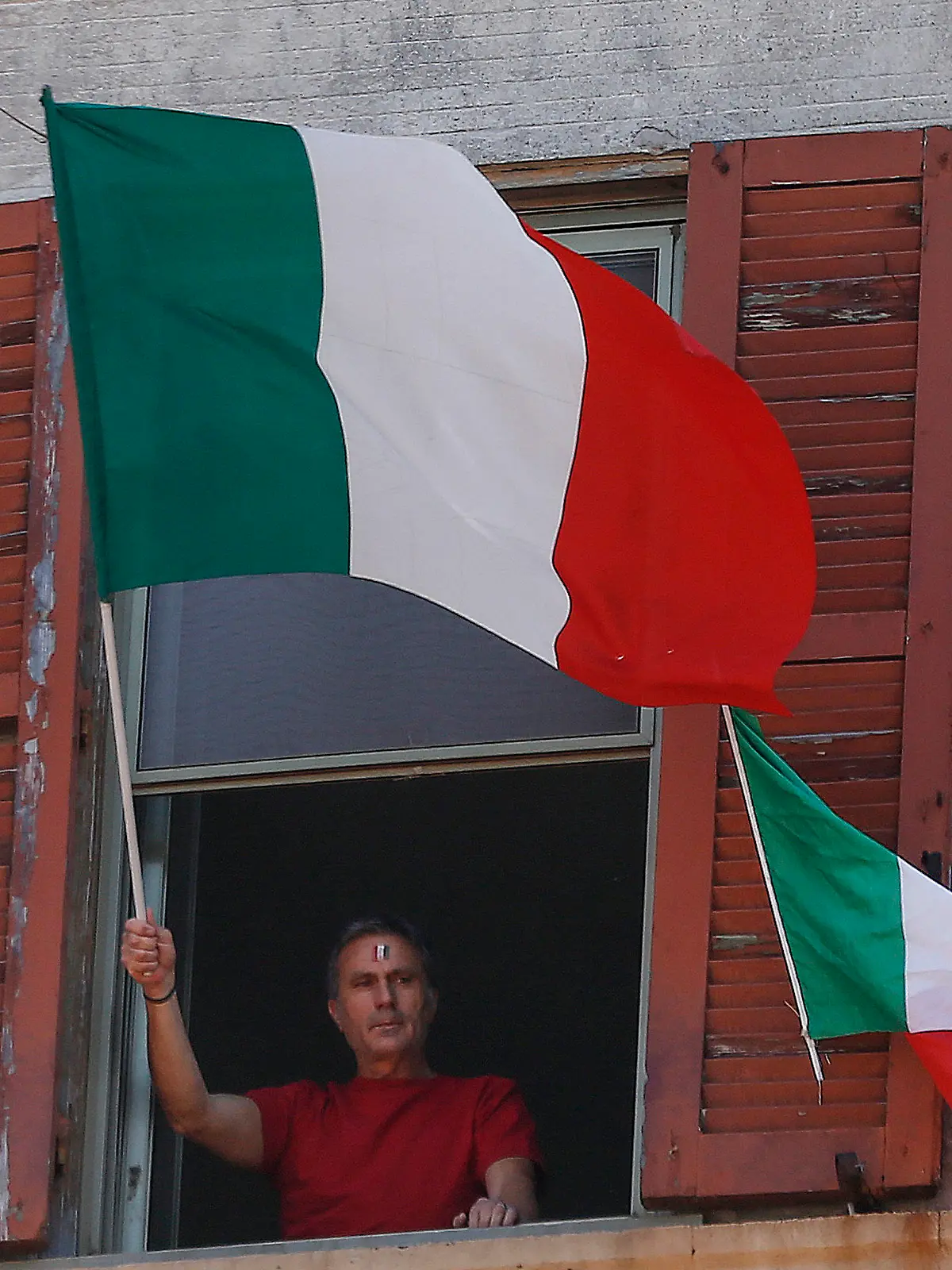 25.04.2020, Italien, Rom: Ein Mann schwenkt am Tag der Befreiung Italiens von seiner Wohnungen aus die italienische Fahne. Die üblichen Märsche in Gedenken an die Befreiung von den Deutschen Besatzern im Zweiten Weltkrieg, können während der Corona-Pandemie nicht stattfinden. Foto: Cecilia Fabiano/LaPresse via ZUMA Press/dpa +++ dpa-Bildfunk +++