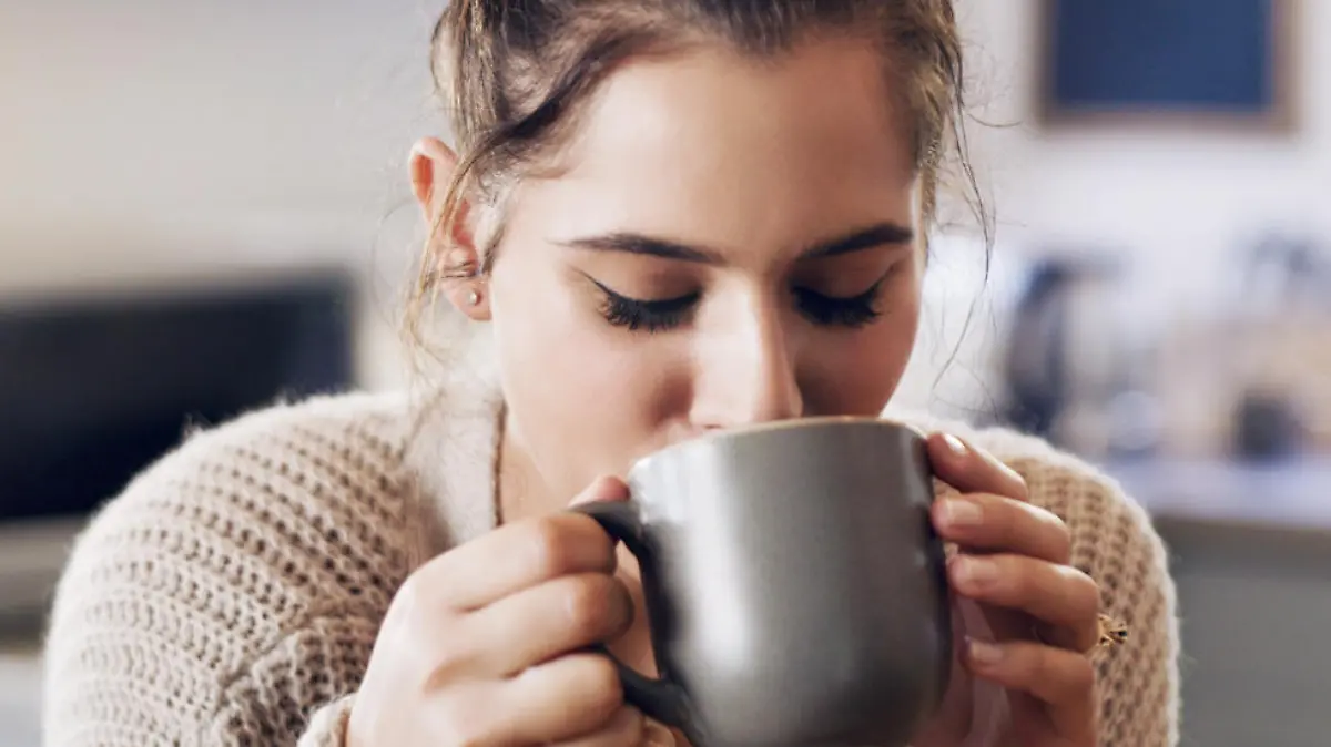 Frau trinkt Kaffee aus Kapselmaschine