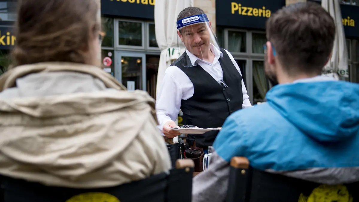 15.05.2020, Sachsen, Leipzig: Ein Kellner bedient Gäste im "Brauhaus an der Thomaskirche". Nach acht Wochen Pause starten viele Kneipen und Restaurants in Sachsen am 15.05. nach dem Lockdown. Etwas Skepsis ist noch da. Die Freude und Erleichterung über den Neustart überwiegt jedoch. Foto: Hendrik Schmidt/dpa-Zentralbild/dpa +++ dpa-Bildfunk +++
