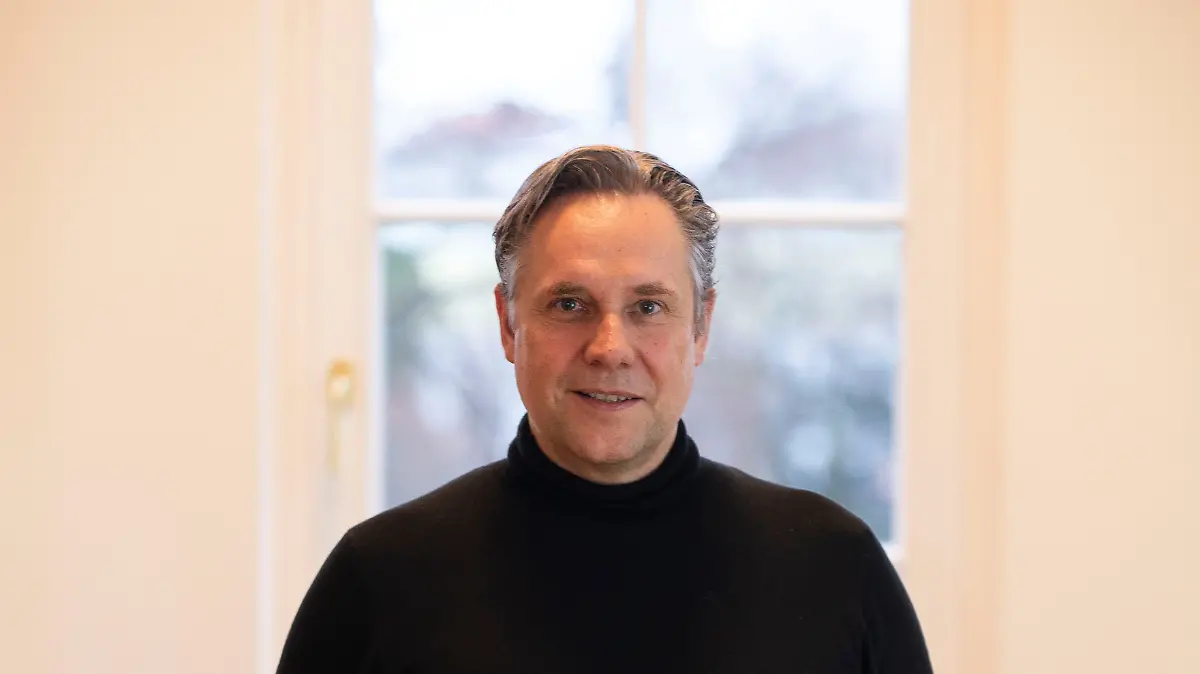 Florian Boitin ist der Chefredakteur von Playboy Deutschland und posiert für das Porträtfoto vor einem Fenster