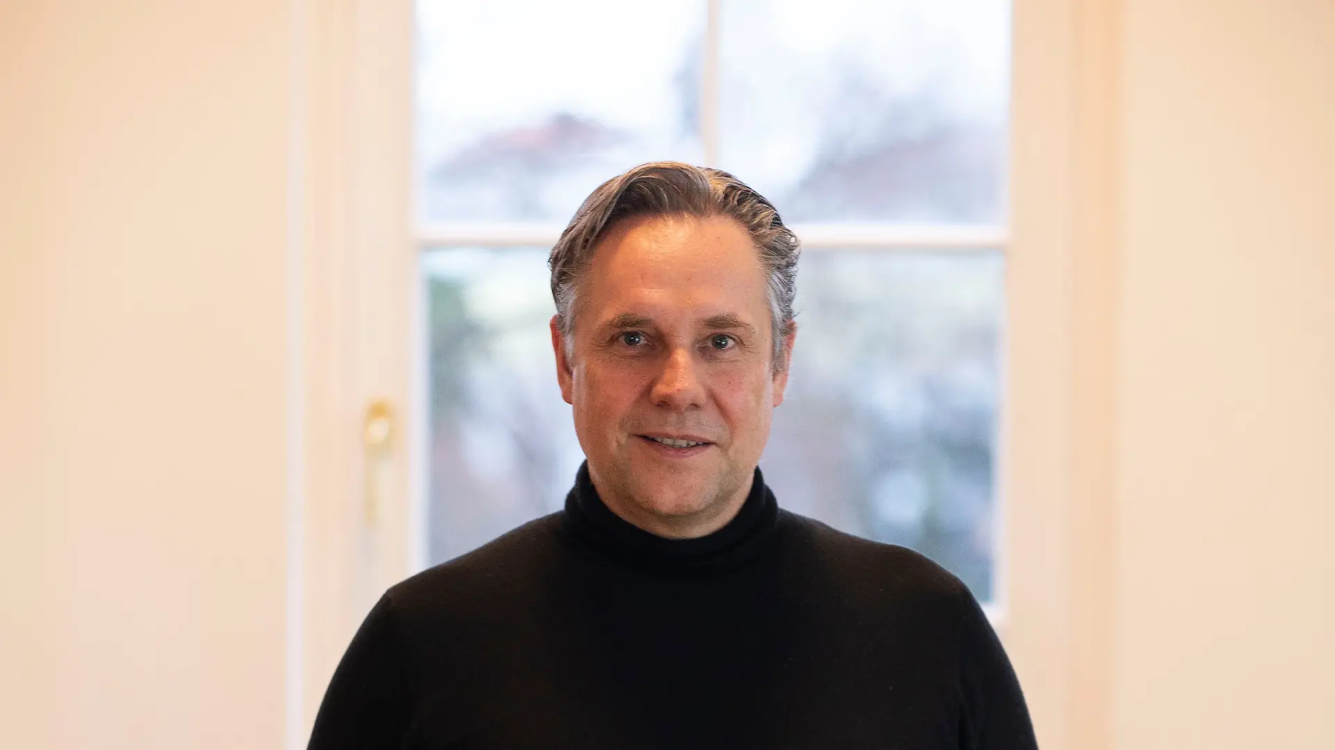 Florian Boitin ist der Chefredakteur von Playboy Deutschland und posiert für das Porträtfoto vor einem Fenster