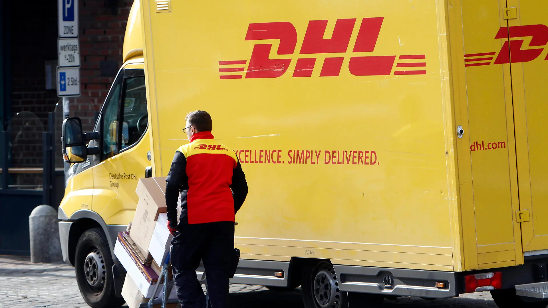  DHL Paketzusteller mit voll beladenem Karren beim Ausliefern von Paketen in der Innenstadt von Hamburg, Deutschland *** DHL parcel delivery staff with fully loaded trolley delivering parcels in the city centre of Hamburg, Germany