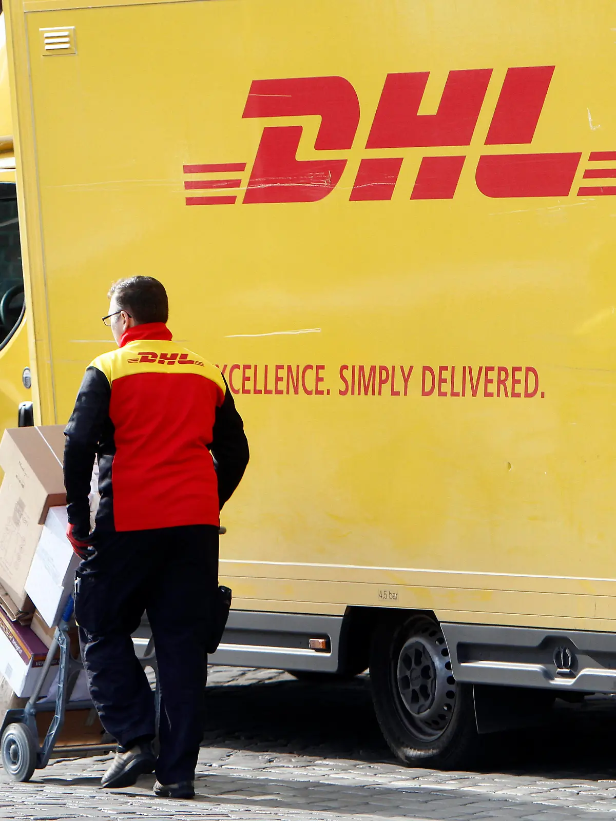  DHL Paketzusteller mit voll beladenem Karren beim Ausliefern von Paketen in der Innenstadt von Hamburg, Deutschland *** DHL parcel delivery staff with fully loaded trolley delivering parcels in the city centre of Hamburg, Germany