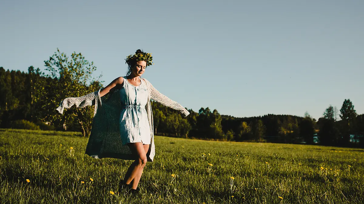 Eine schwedische Frau tanzt im Feld am Mittsommerfest.