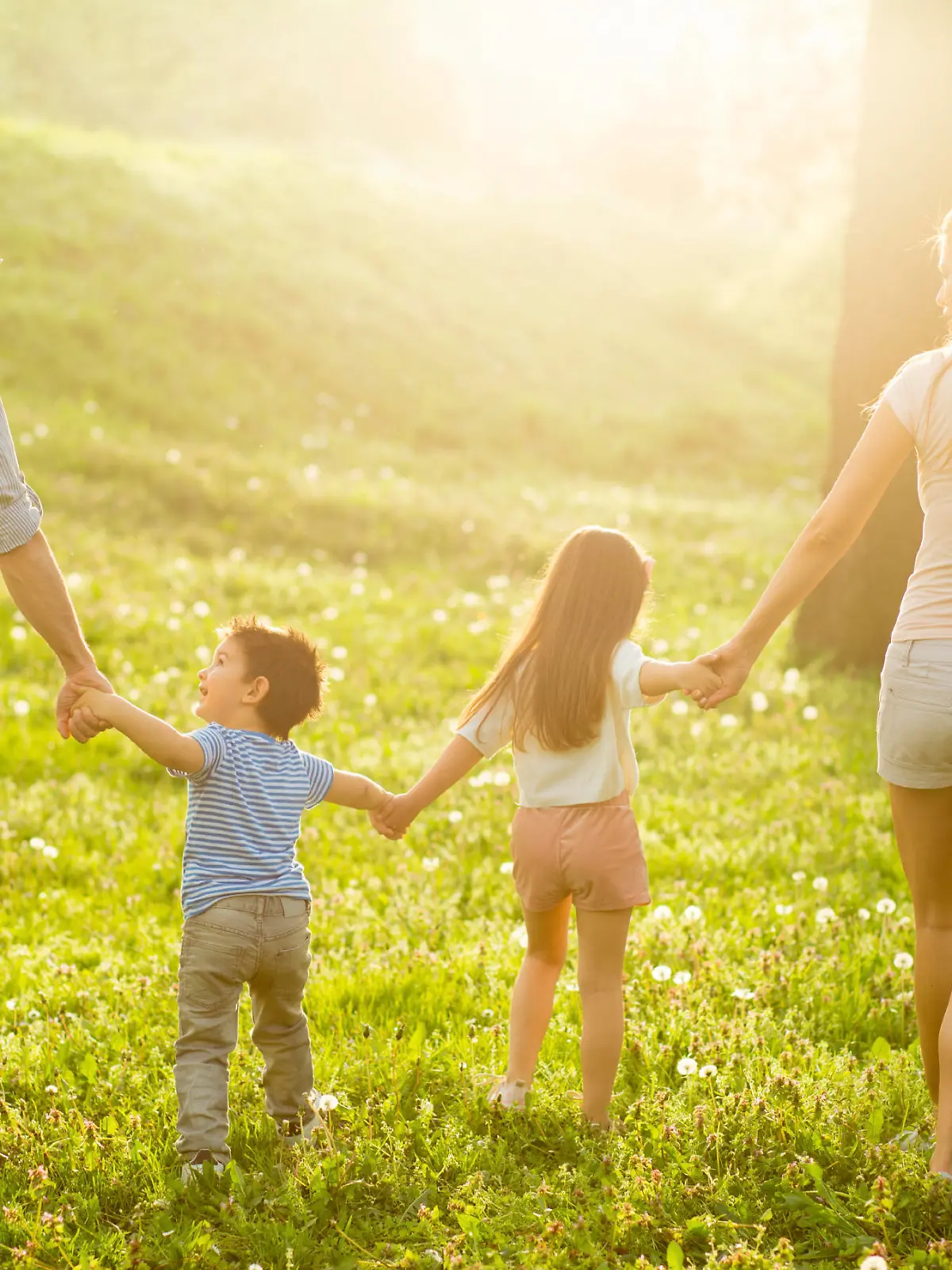 Young smiling parents holding hands and walking with their children in nature