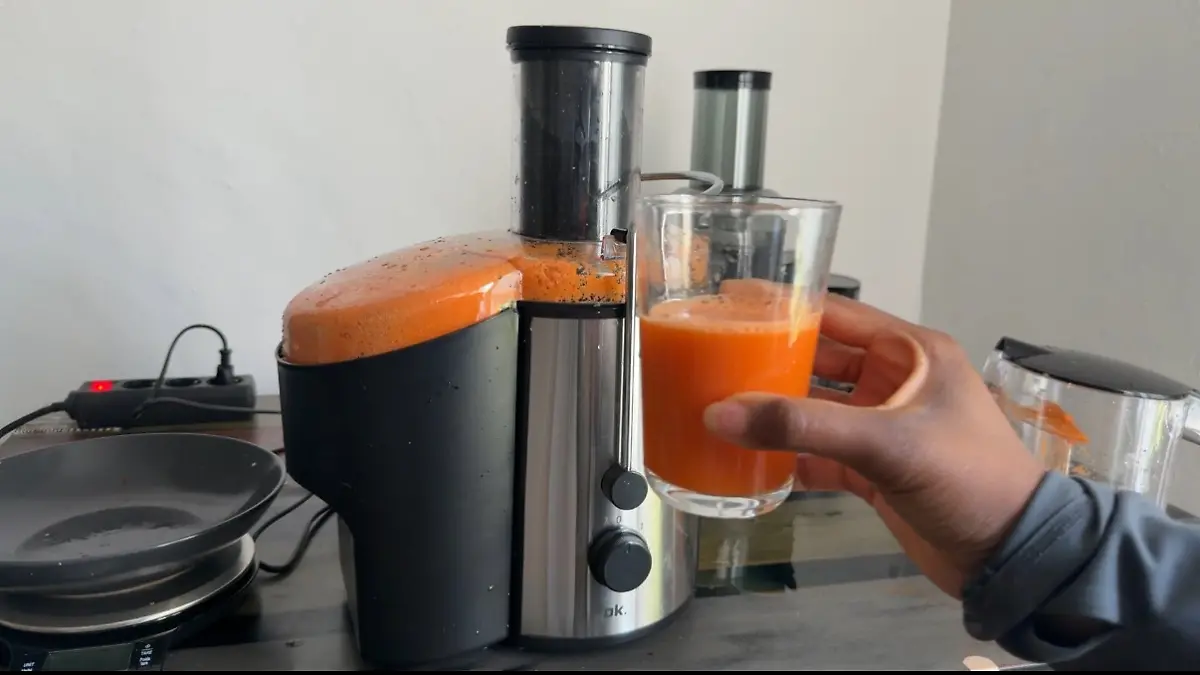 Ein Glas mit orangem Möhrensaft vor dem OK.-Zentrifugalentsafter