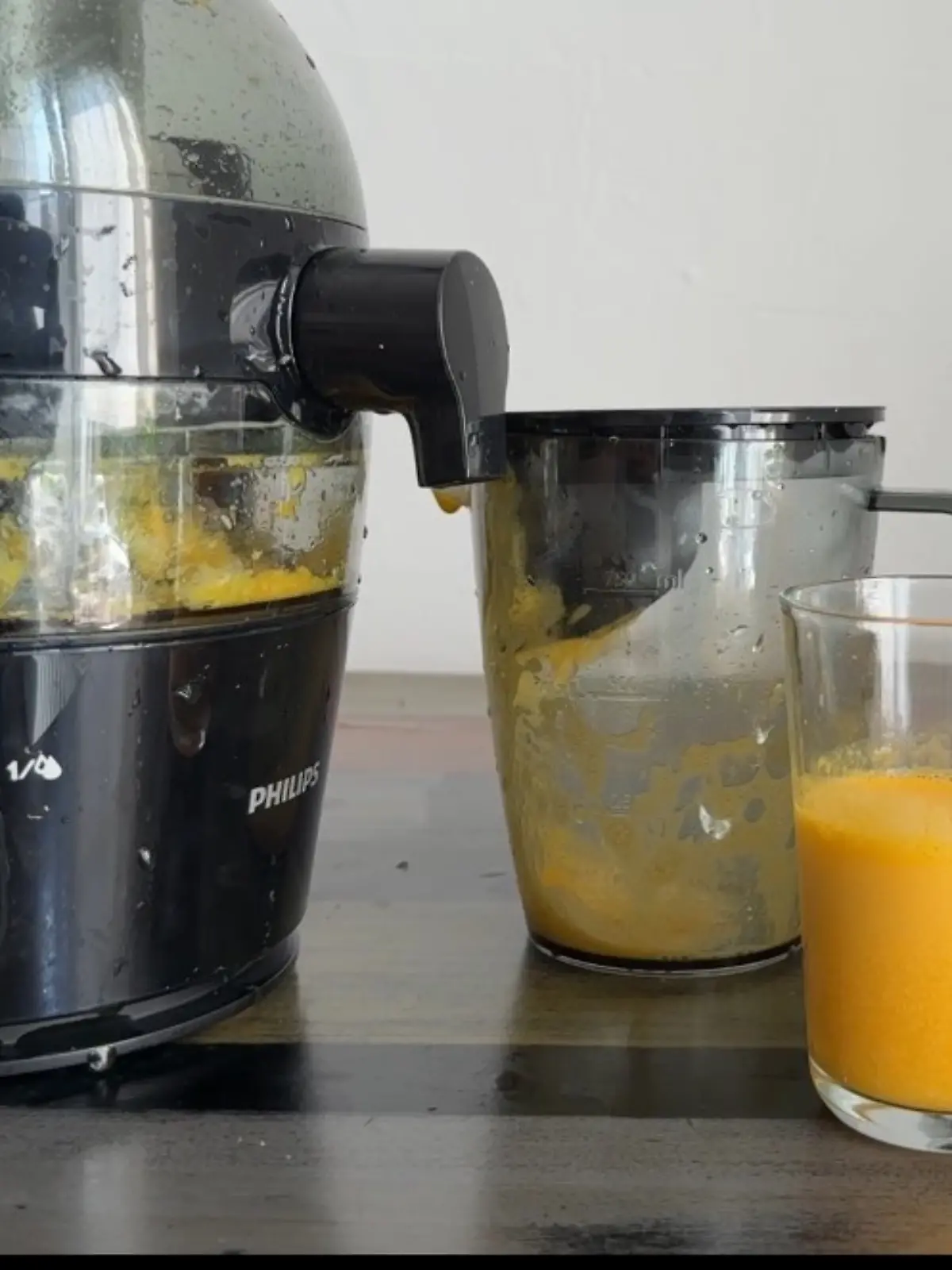 Zwei Gläser mit frisch gepresstem Orangensaft vor dem Philips-Entsafter mit sichtbarem Tresterbehälter