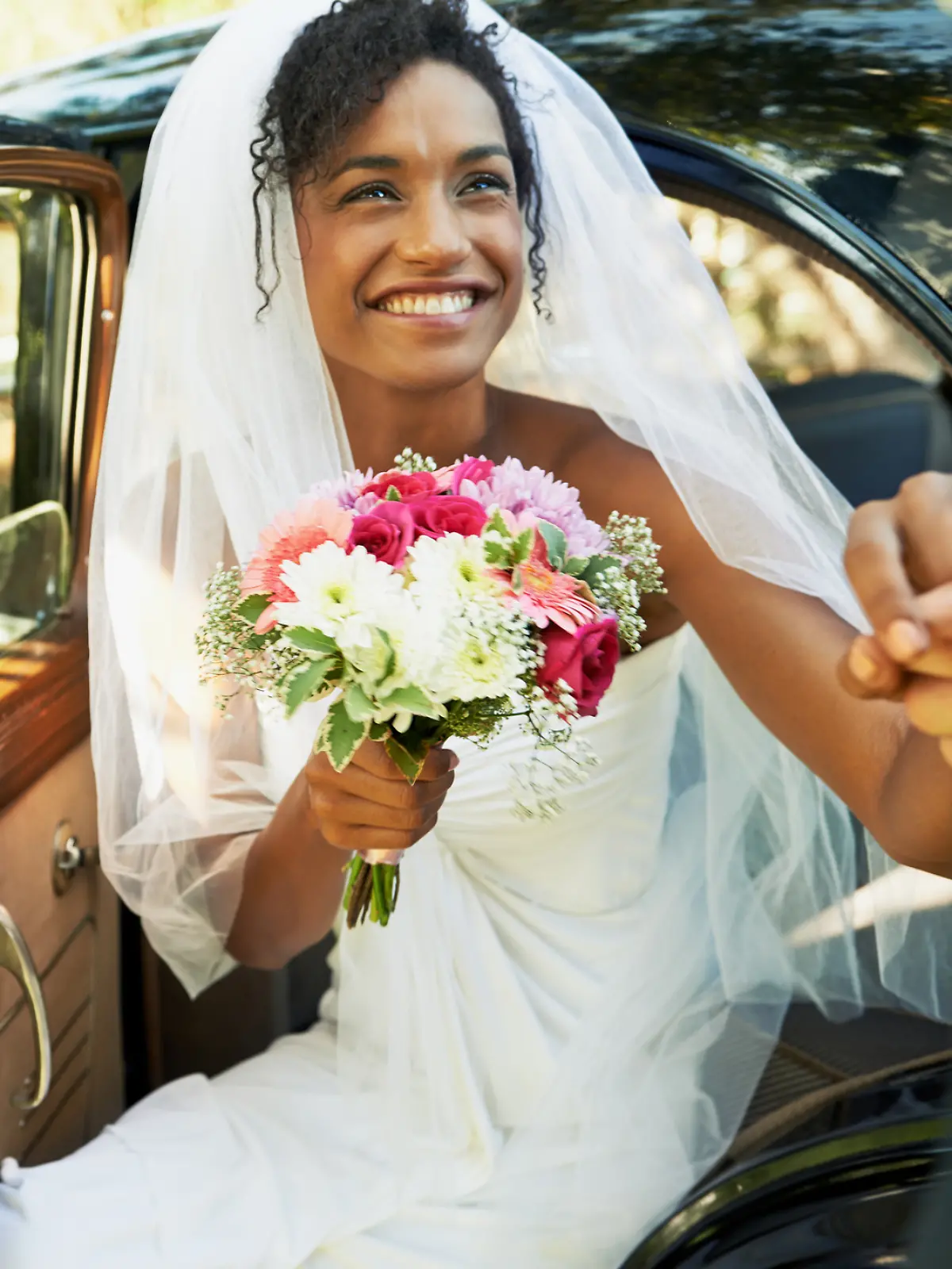 Braut in Brautkleid steigt aus dem Auto.