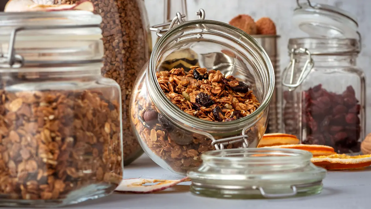 Glass jars with muesli in a on table in kitchen or pantry for topping, ingredients of dessert or breakfast.