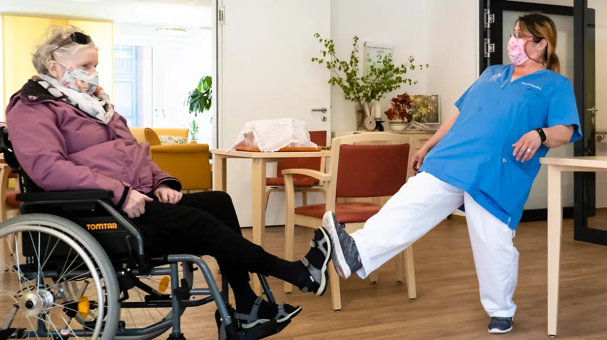 24.04.2020, Schleswig-Holstein, Kiel: Altenpflegerin Jaqueline Ackermann (r) und Bewohnerin Karin Plagemann begrüßen sich per Fuß im Kurt-Engert-Haus im Stadtteil Holtenau. In der Pflege- und Senioreneinrichtung der Stiftung Kieler Stadtkloster gilt seit dem 18. März 2020 ein Besuchsverbot. (zu dpa "Corona-Isolation in Pflegeheimen mit fatalen Folgen") Foto: Frank Molter/dpa +++ dpa-Bildfunk +++