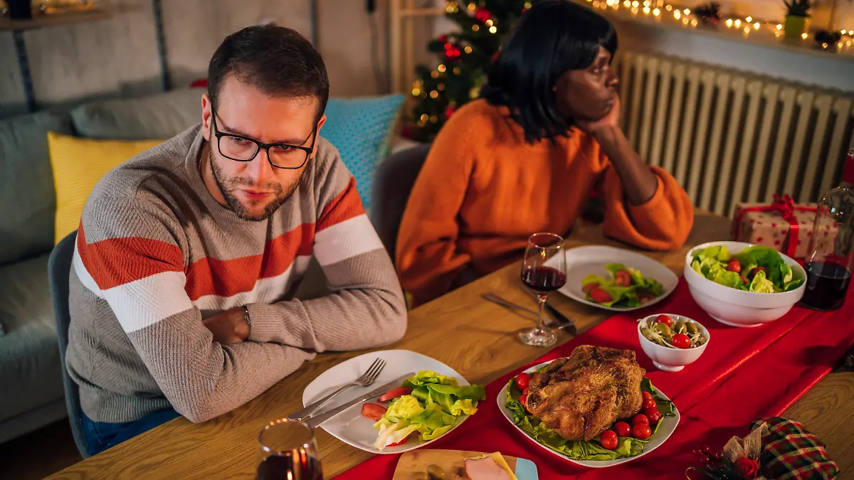 Young unhappy multi ethnic couple ignoring each other after an argument during Christmas dinner