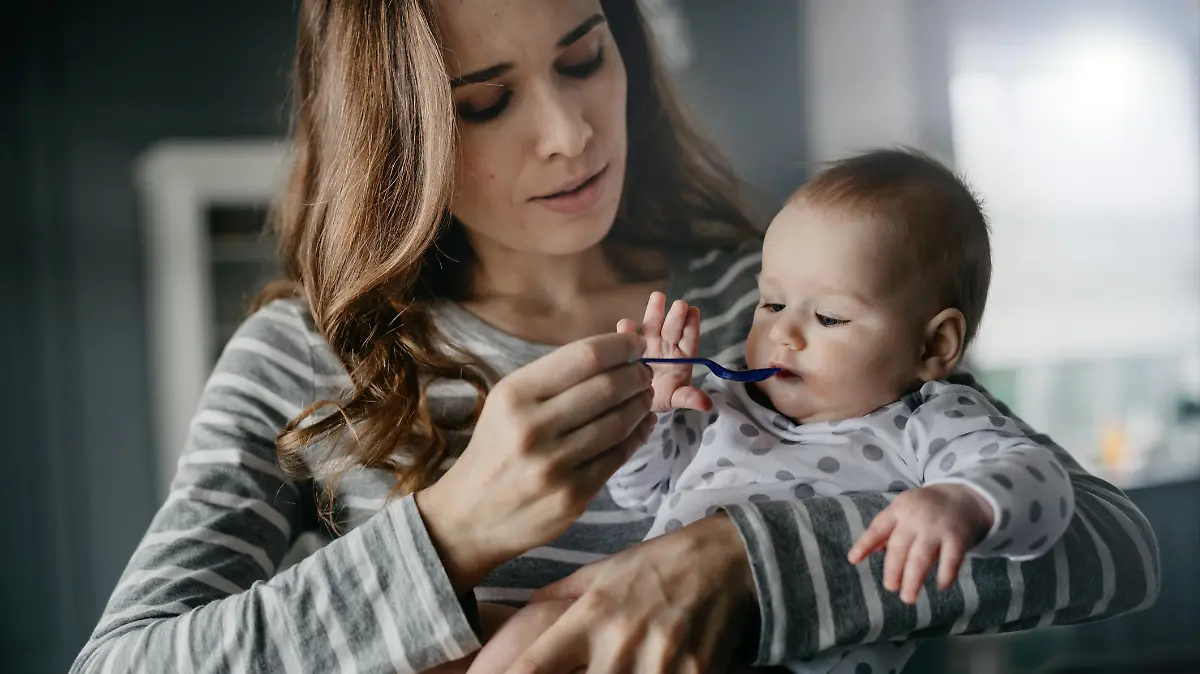 Mutter füttert Baby mit Löffel