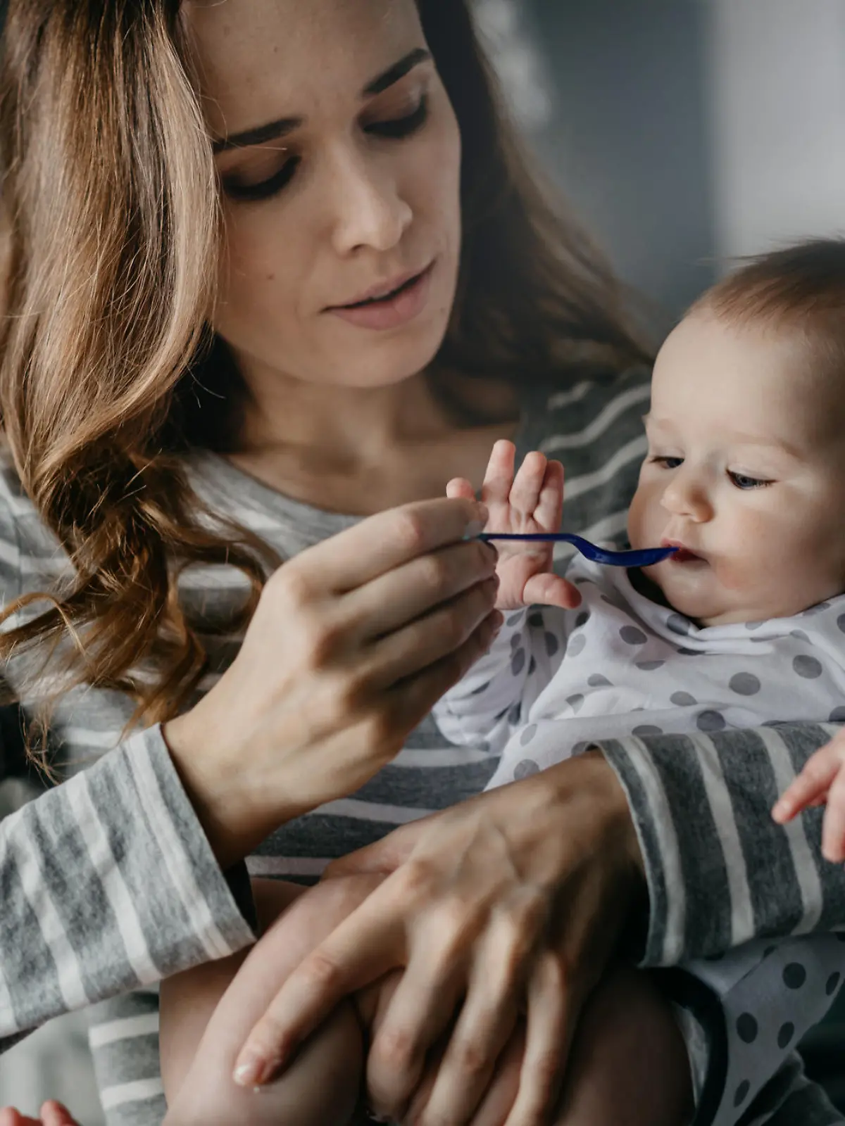 Mutter füttert Baby mit Löffel