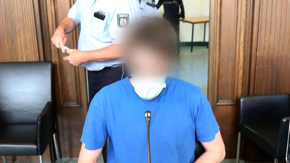 12.05.2020, Nordrhein-Westfalen, Moers: Der Angeklagte (vorne) wartet unter den Augen eines Justizbeamten auf den Beginn seines Prozesses. Der 26 Jahre alte Soldat soll kleine Kinder in insgesamt 33 Fällen missbraucht haben, teilweise schwer und zwei Mal zusammen mit einem Chat-Partner. Foto: Roland Weihrauch/dpa Pool/dpa - ACHTUNG: Person(en) wurde(n) aus rechtlichen Gründen gepixelt +++ dpa-Bildfunk +++
