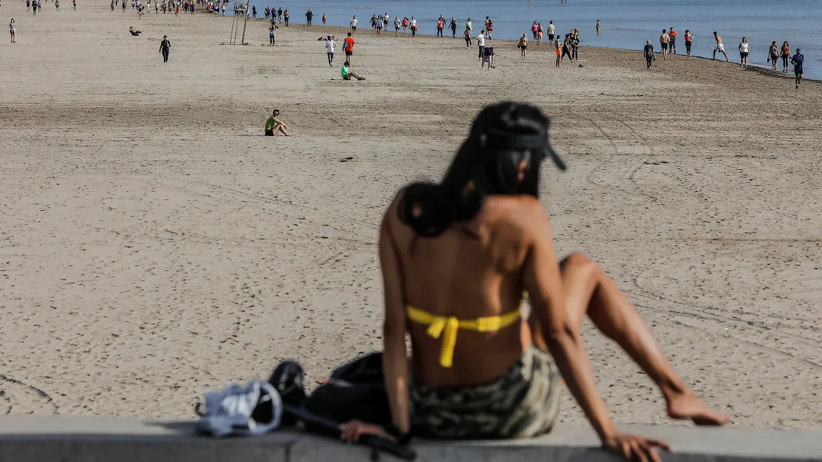 02.05.2020, Spanien, Valencia (comunidad Valenciana): Eine Frau sitzt in ihrem Bikini am Strand von Malvarrosa. Ab diesem Wochenende dürfen die Bürger im von der Corona-Pandemie schwer betroffenen Spanien erstmals nach sieben Wochen wieder im Freien spazieren gehen oder Sport treiben. Foto: Rober Solsona/Europa Press/dpa +++ dpa-Bildfunk +++