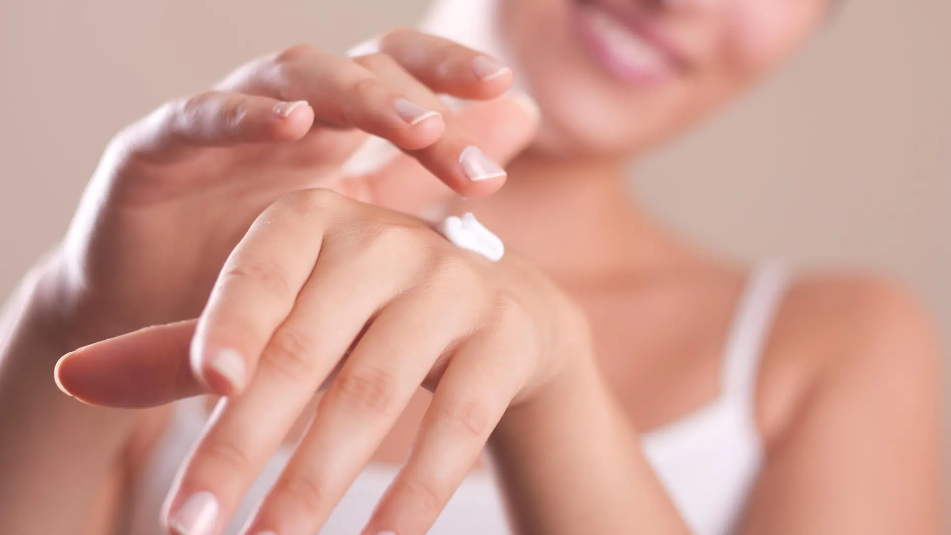 closeup of female hands applying hand cream