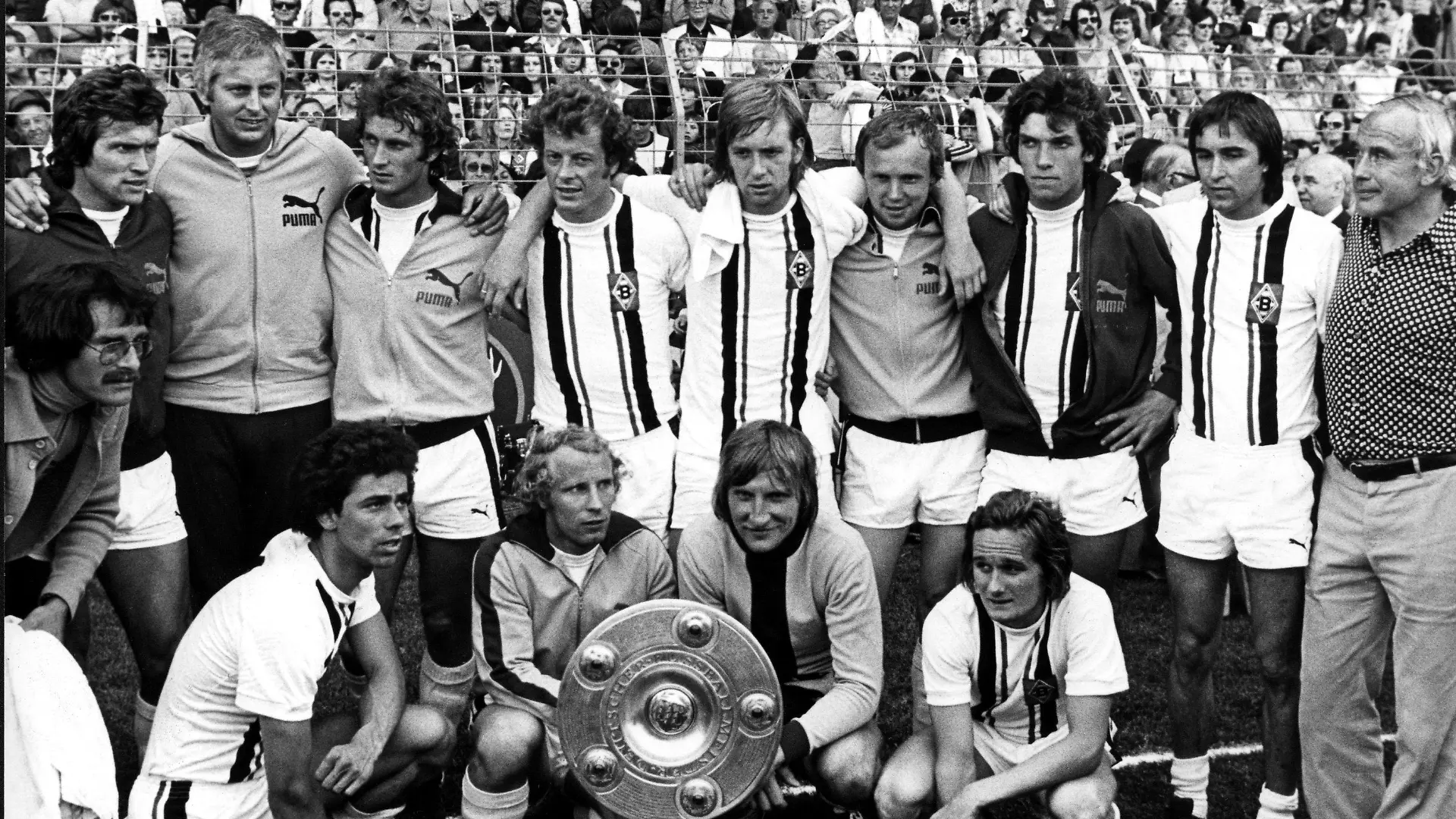 ARCHIV - 07.06.1975, Nordrhein-Westfalen, Mönchengladbach: Gruppenbild des Deutschen Meisters Borussia Mönchengladbach nach dem Sieg am vorletzten Spieltag der Bundesliga gegen Eintracht Braunschweig in Mönchengladbach. (Stehend v.l.n.r) Jupp Heynckes, Trainerassistent Karl-Heinz Drygalski, Rainer Bonhof, Wimmer, Jensen, Wittkamp, Schäffer, Danner und «Meistermacher» Trainer Hennes Weisweiler. (Vorn v.l.n.r) Masseur Stock, Klinkhammer, Berti Vogts, Kleff und Alan Simonsen. (zu "Keine große Bühne mehr: Heynckes sinniert zum 75. über Gesellschaft") Foto: Scheidemann/dpa +++ dpa-Bildfunk +++