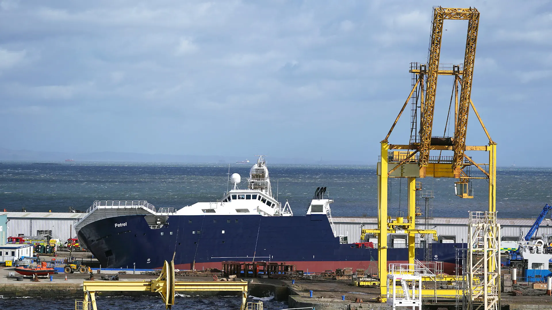 22.03.2023, Großbritannien, Leith: Rettungskräfte arbeiten am Imperial Dock, wo sich ein Schiff aus seiner Halterung gelöst hat, teilweise umgekippt ist und mehrere Personen verletzt hat. Starker Wind könnte zu dem Vorfall beigetragen haben, twitterte Gemeinderatsmitglied Adam McVey. Foto: Andrew Milligan/PA Wire/dpa +++ dpa-Bildfunk +++