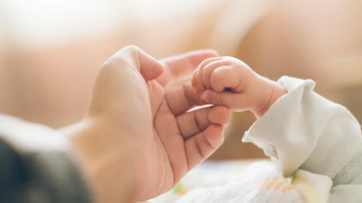 Baby ertastet den FInger des Vaters