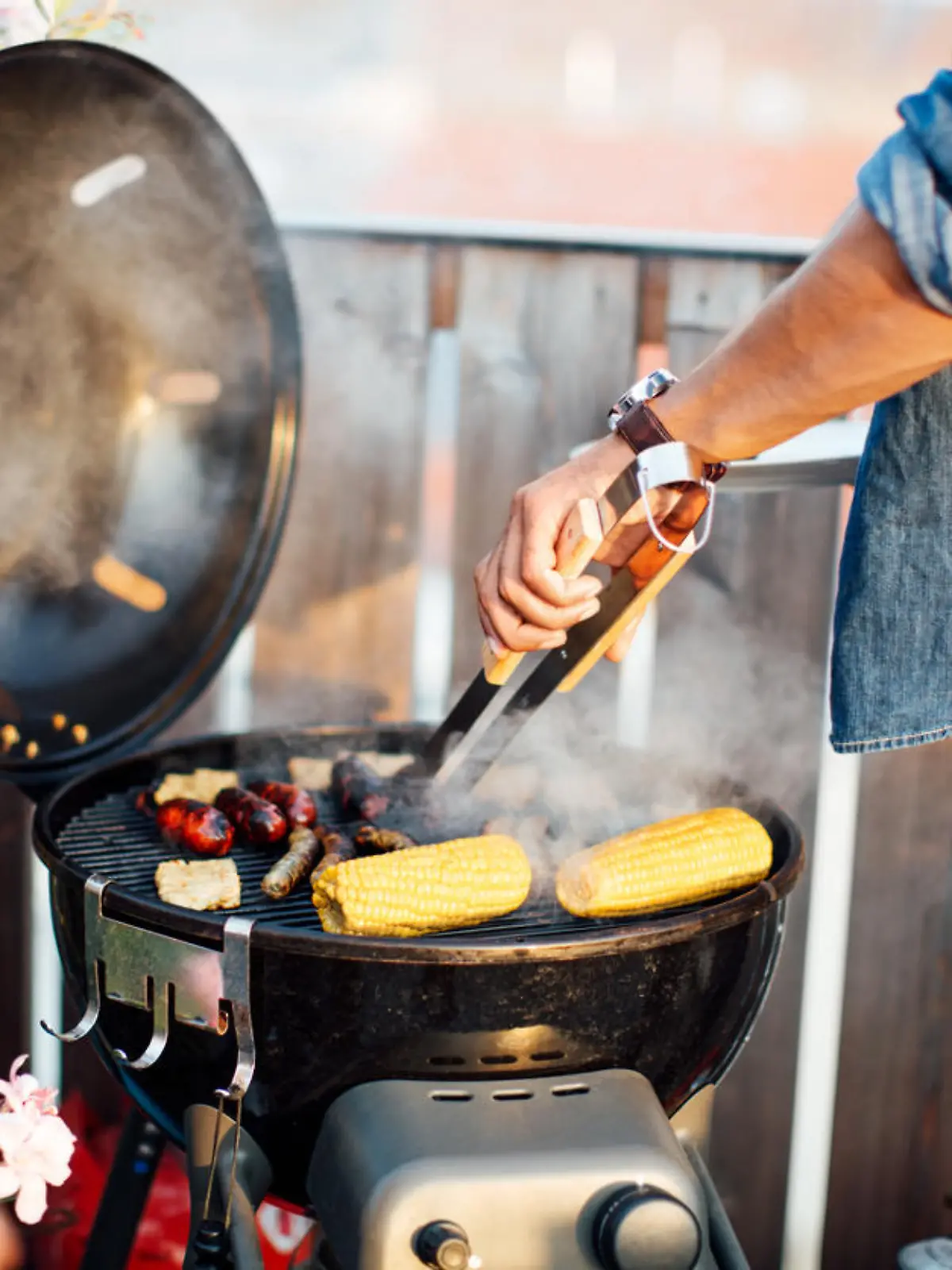 Mann grillt auf einem Balkon.