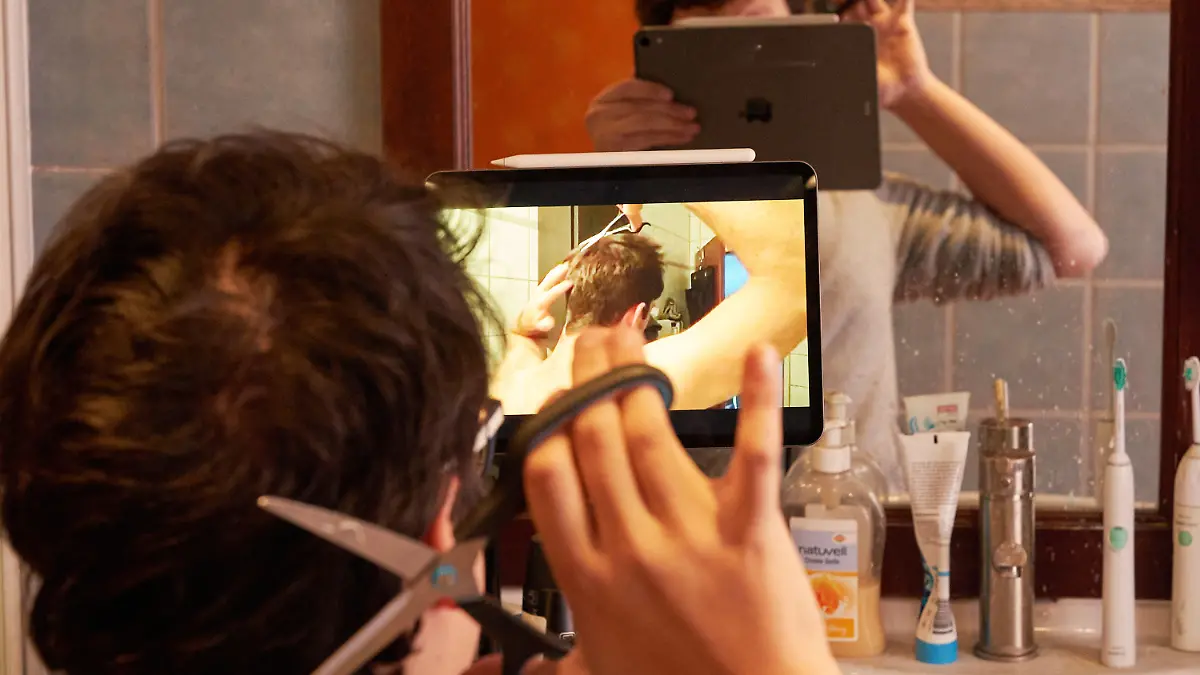 ARCHIV - 01.04.2020, Rheinland-Pfalz, Koblenz: Ein junger Mann schneidet sich nach Anleitung eines Online-Tutorials selber die Haare. Seit die Friseursalons wegen der Kontaktbeschränkungen aufgrund der Ausbreitung des Coronavirus geschlossen sind, gibt es viele Abrufe von Haarschnitt-Tutorials auf den Videoplattformen. (zu dpa «Chaos auf dem Kopf: Das Ende naht») Foto: Thomas Frey/dpa +++ dpa-Bildfunk +++