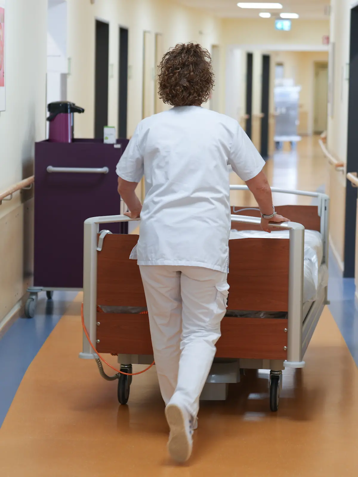 Eine Krankenschwester schiebt ein Bett über den Flur einer Krankenstation in der Asklepios Klinik Bad Oldesloe.