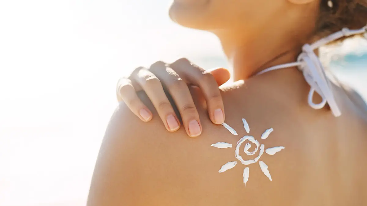 Frau schützt sich mit Sonnenmilch