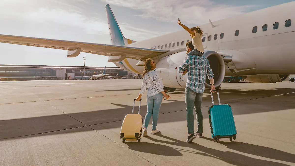Junge Familie mit Kind vor einem Flugzeug.