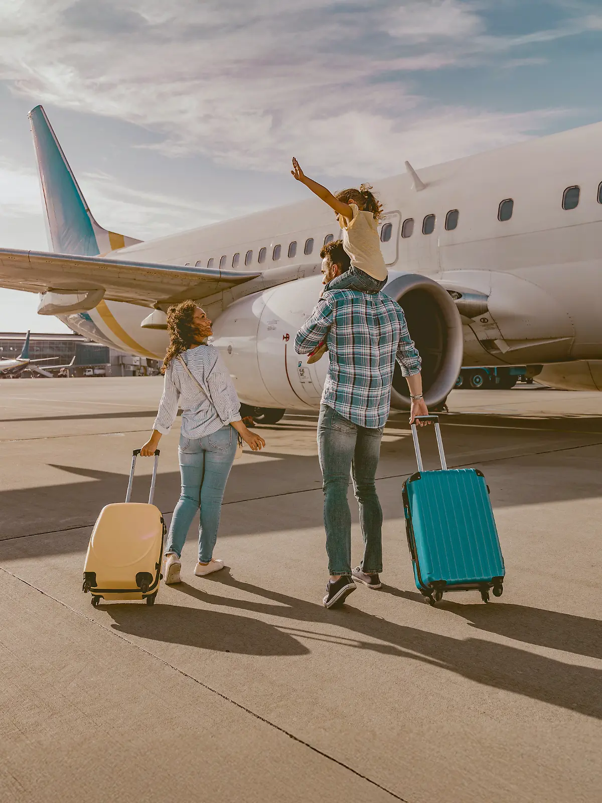 Junge Familie mit Kind vor einem Flugzeug.