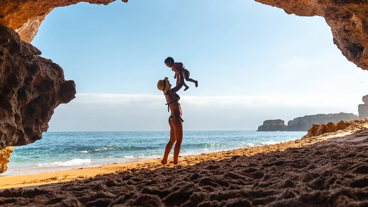 Eine Frau spielt mit ihrem Sohn an der Algarve, der portugiesischen Küste.