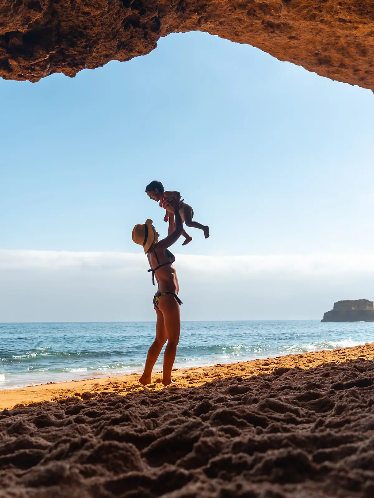 Eine Frau spielt mit ihrem Sohn an der Algarve, der portugiesischen Küste.