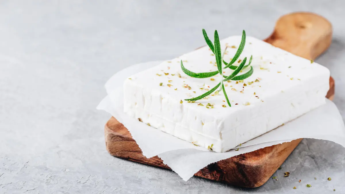 Homemade greek cheese feta with rosemary and herbs on wooden cutting board