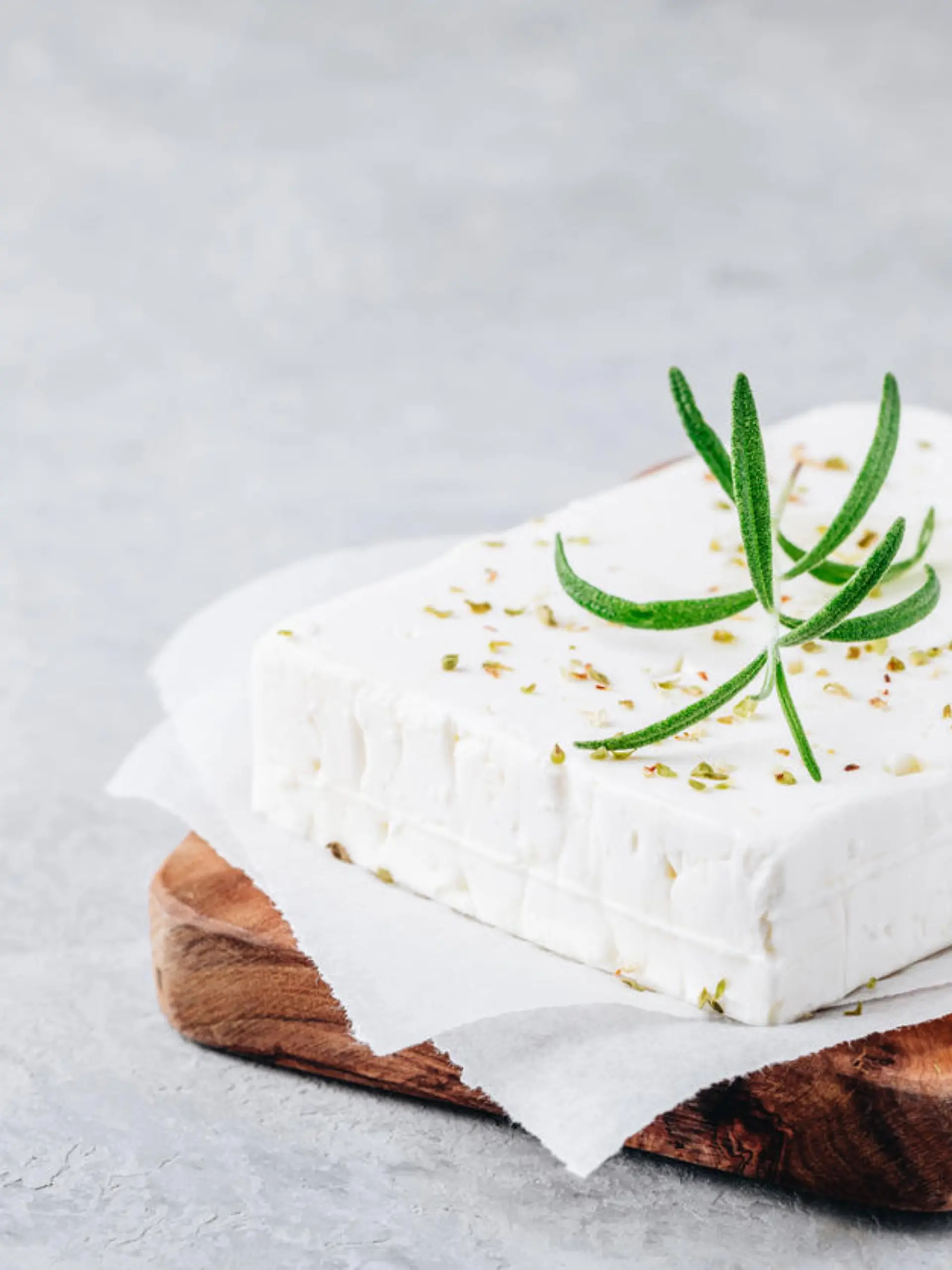 Homemade greek cheese feta with rosemary and herbs on wooden cutting board