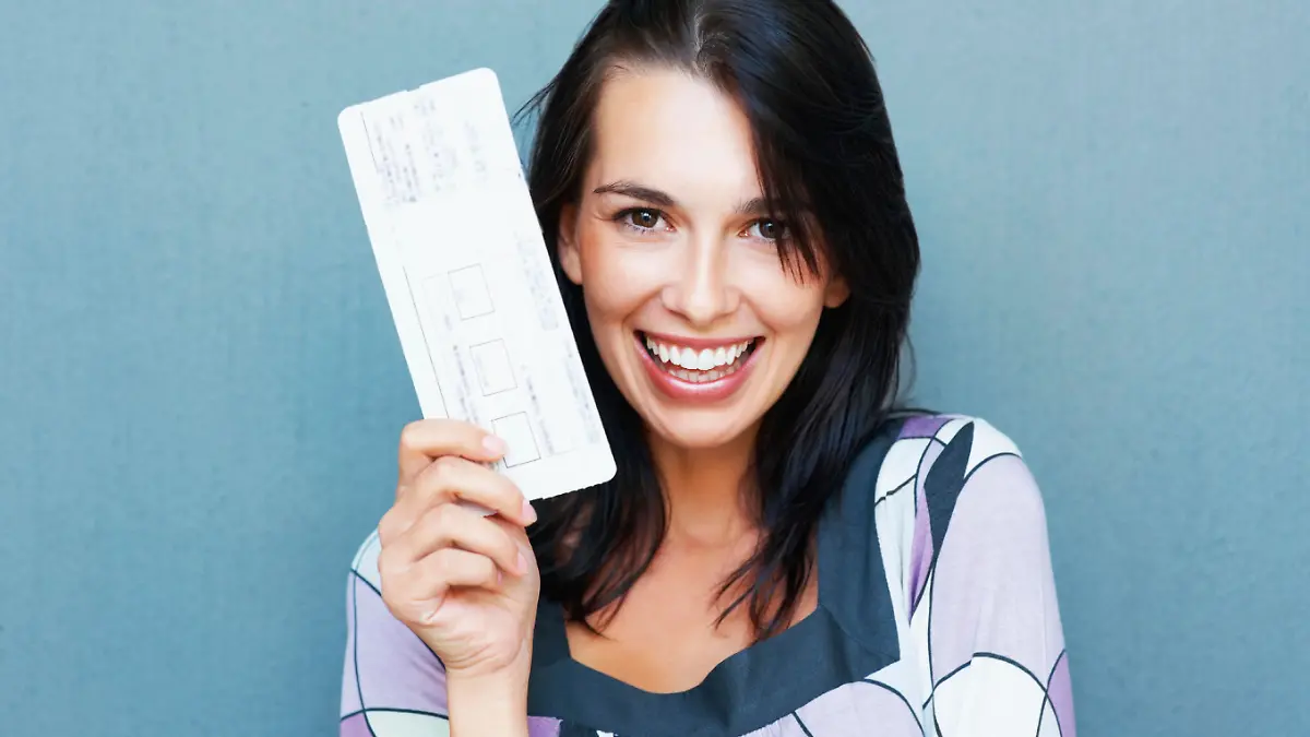 Closeup portrait of smiling young woman holding boarding pass