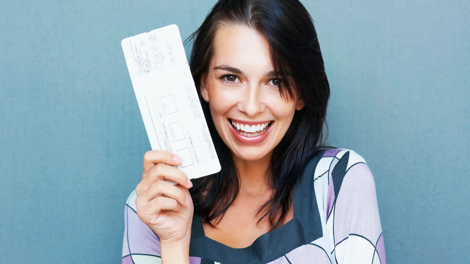 Closeup portrait of smiling young woman holding boarding pass