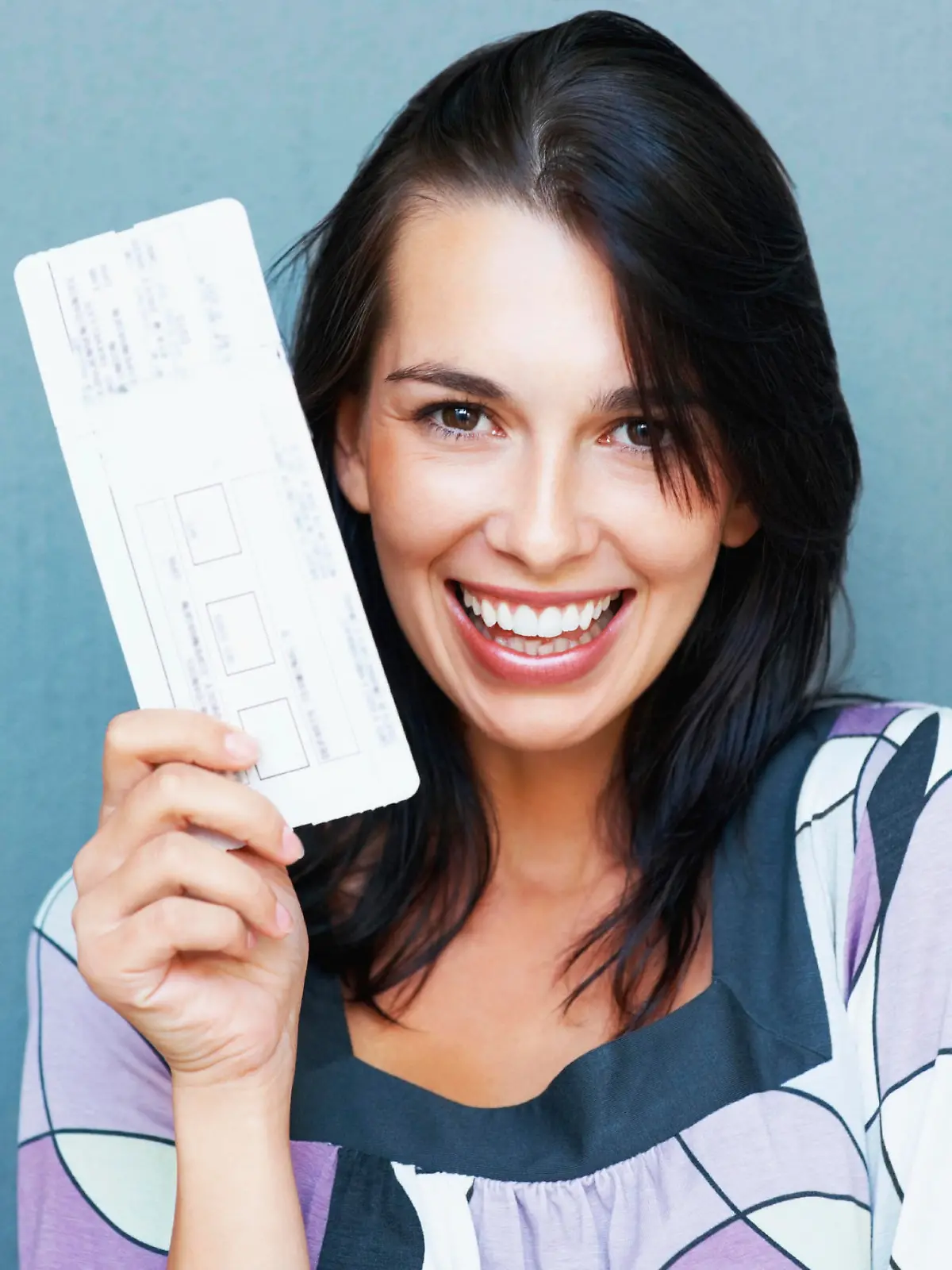 Closeup portrait of smiling young woman holding boarding pass