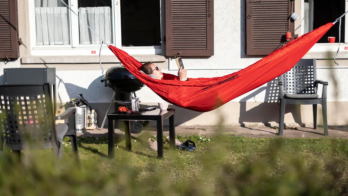 04.04.2020, Baden-Württemberg, Freiburg: Maja liegt in einer roten Hängematte und liest ein Buch. Foto: Patrick Seeger/dpa +++ dpa-Bildfunk +++