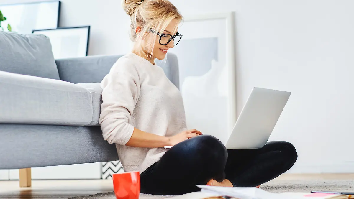 Junge Frau am Boden ihrer Wohnung mit Notebook