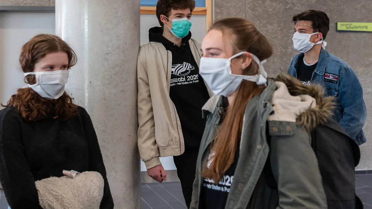 20.04.2020, Sachsen, Dresden: Abiturienten am Gymnasium Dresden Klotzsche stehen vor Beginn der Konsultationen im Treppenhaus und tragen einen Mundschutz. Nach einem Monat weitgehenden Stillstands wegen der Eindämmung des Coronavirus in Deutschland werden am heutigen Montag die ersten Corona-Auflagen schrittweise gelockert. Die ersten Schüler kommen in Sachsen für Prüfungsvorbereitungen in die Schulen zurück. Foto: Robert Michael/dpa-Zentralbild/dpa +++ dpa-Bildfunk +++