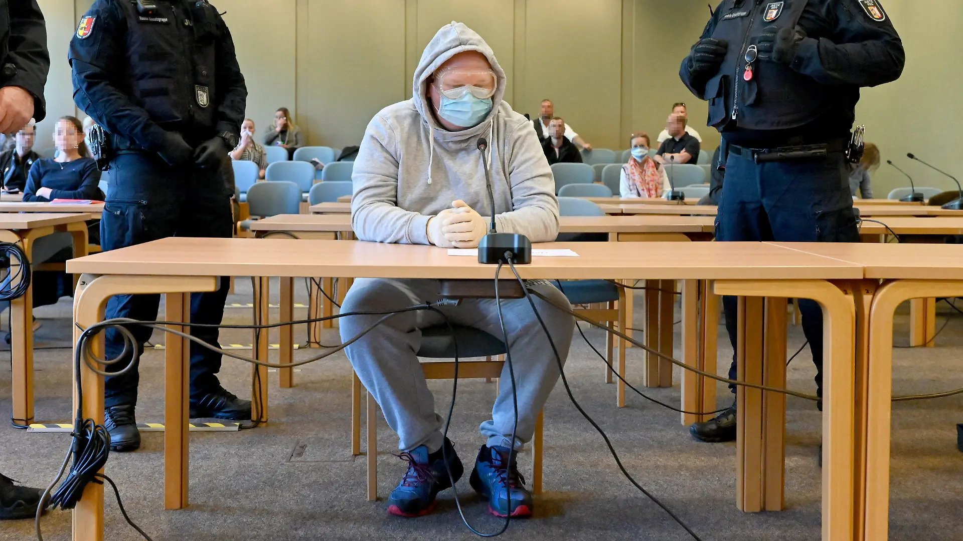23.04.2020, Schleswig-Holstein, Schleswig: Mit Schutzbrille und Mundschutz sitzt der 47-Jährige Angeklagte beim Auftakt des Verfahrens im Gerichtssaal. Er soll die 23-Jährige Nathalie M., die sexuelle Dienstleistungen im Internet angeboten haben soll, am 17.8.2019 bei Schafflund getötet und an einem Feldweg bei Süderlügum verscharrt haben. Die Leiche wurde zwei Wochen später gefunden. Foto: Carsten Rehder/dpa - ACHTUNG: Personen wurden aus rechtlichen Gründen gepixelt +++ dpa-Bildfunk +++
