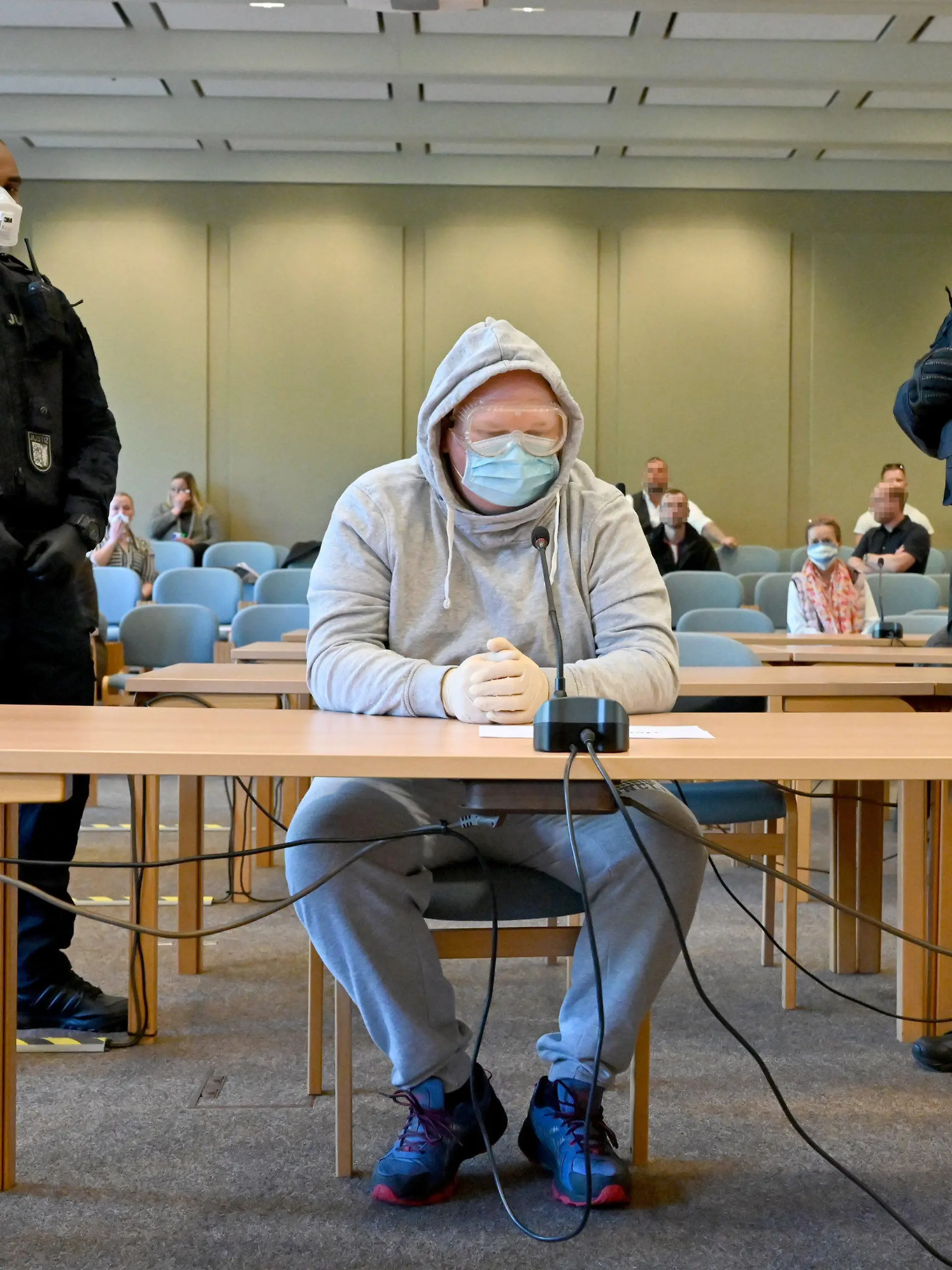 23.04.2020, Schleswig-Holstein, Schleswig: Mit Schutzbrille und Mundschutz sitzt der 47-Jährige Angeklagte beim Auftakt des Verfahrens im Gerichtssaal. Er soll die 23-Jährige Nathalie M., die sexuelle Dienstleistungen im Internet angeboten haben soll, am 17.8.2019 bei Schafflund getötet und an einem Feldweg bei Süderlügum verscharrt haben. Die Leiche wurde zwei Wochen später gefunden. Foto: Carsten Rehder/dpa - ACHTUNG: Personen wurden aus rechtlichen Gründen gepixelt +++ dpa-Bildfunk +++