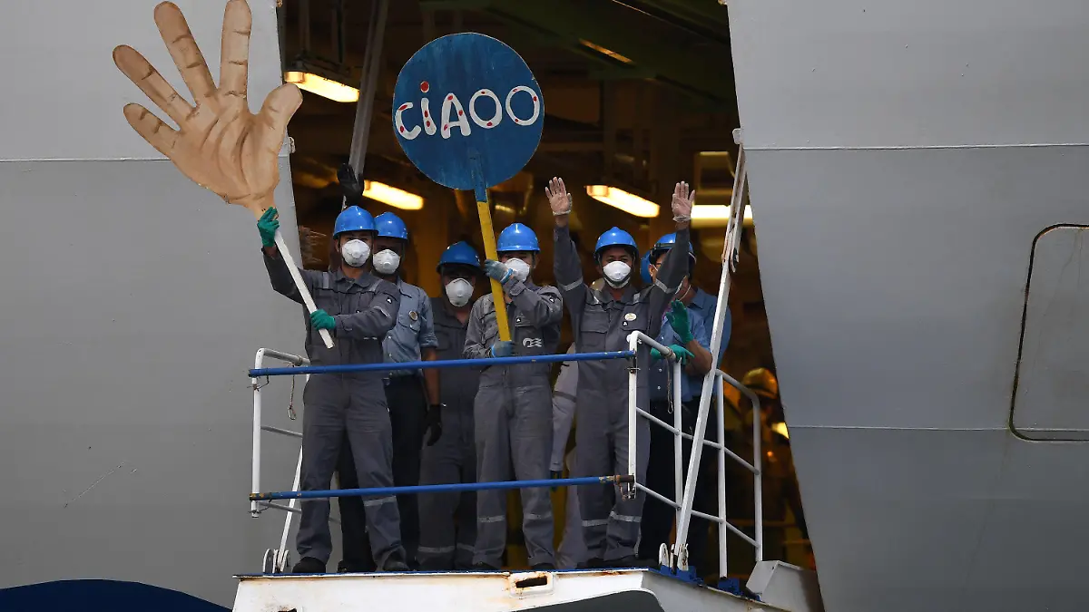 dpatopbilder - 23.04.2020, Australien, Wollongong: Besatzungsmitglieder der «Ruby Princess» winken mit Pappschildern in Form einer Hand und der Aufschrift «Ciaoo», als das Schiff den Hafen des Küstenvororts Port Kembla verlässt. Das Kreuzfahrtschiff, der größte Corona-Brennpunkt in Australien, hat den Kontinent in Richtung der Philippinen verlassen. Foto: Dean Lewins/AAP/dpa +++ dpa-Bildfunk +++