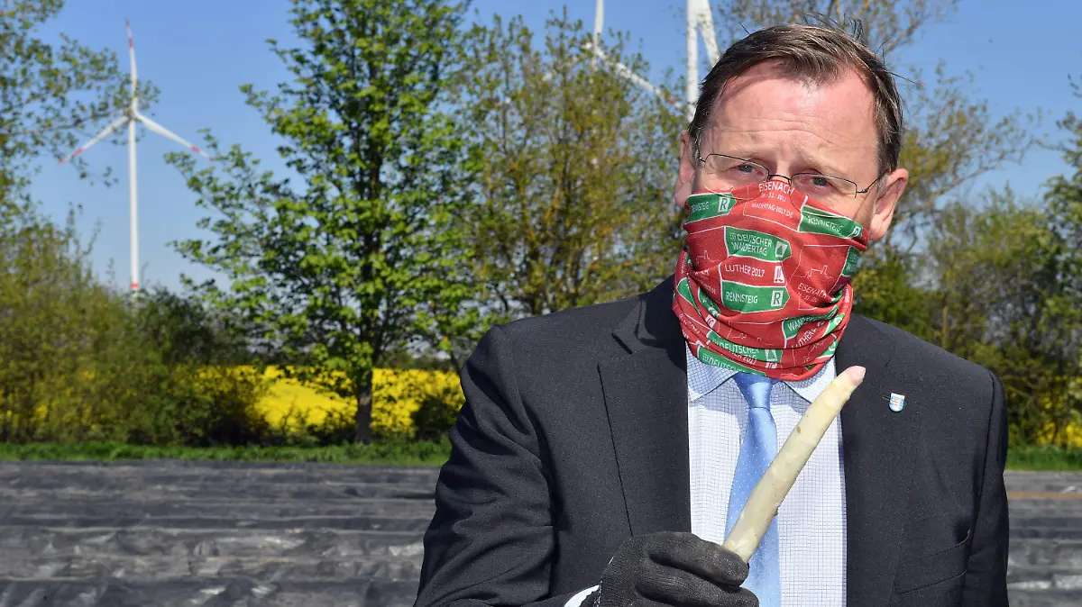 22.04.2020, Thüringen, Kutzleben: Bodo Ramelow (Die Linke), Ministerpräsident von Thüringen, präsentiert eine Spargelstange auf einem Feld des Spargelhofs Kutzleben. Der Betrieb im Unstrut-Hainich-Kreis ist einer der größten Spargelanbauer in Thüringen. Hier starten am selben Tag rumänische Erntehelfer bei der Spargelernte. Foto: Martin Schutt/dpa-Zentralbild/dpa +++ dpa-Bildfunk +++
