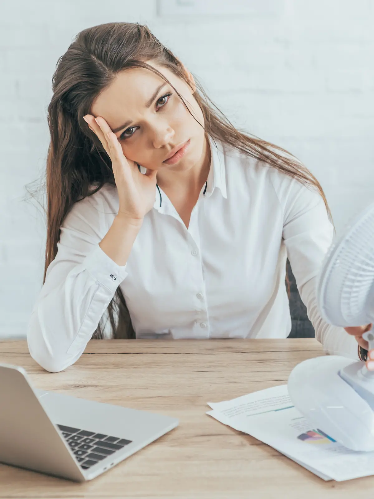 Einer Frau ist warm und schwitzt im Büro