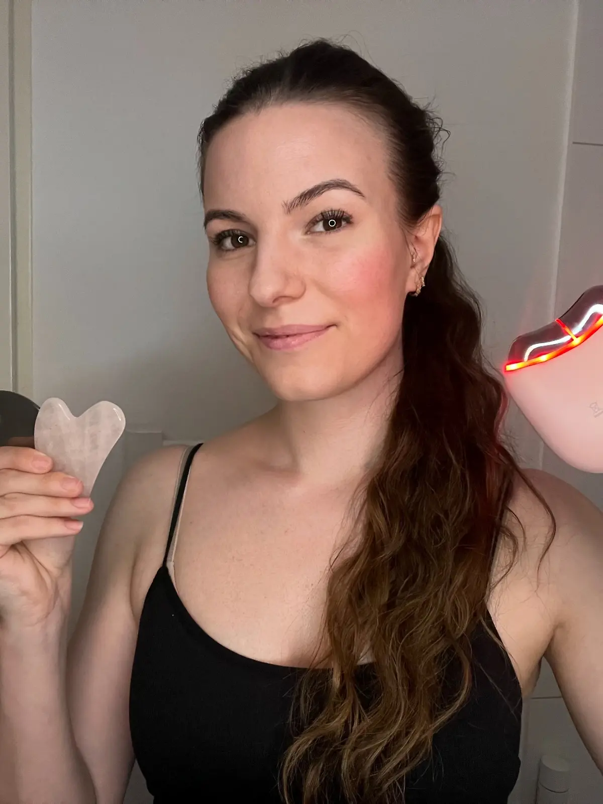 Isabelle Kurz hält drei Gua Shas in ihren Händen. Einen aus Edelstahl, einen aus Rosenquarz und ein EMS-Modell.