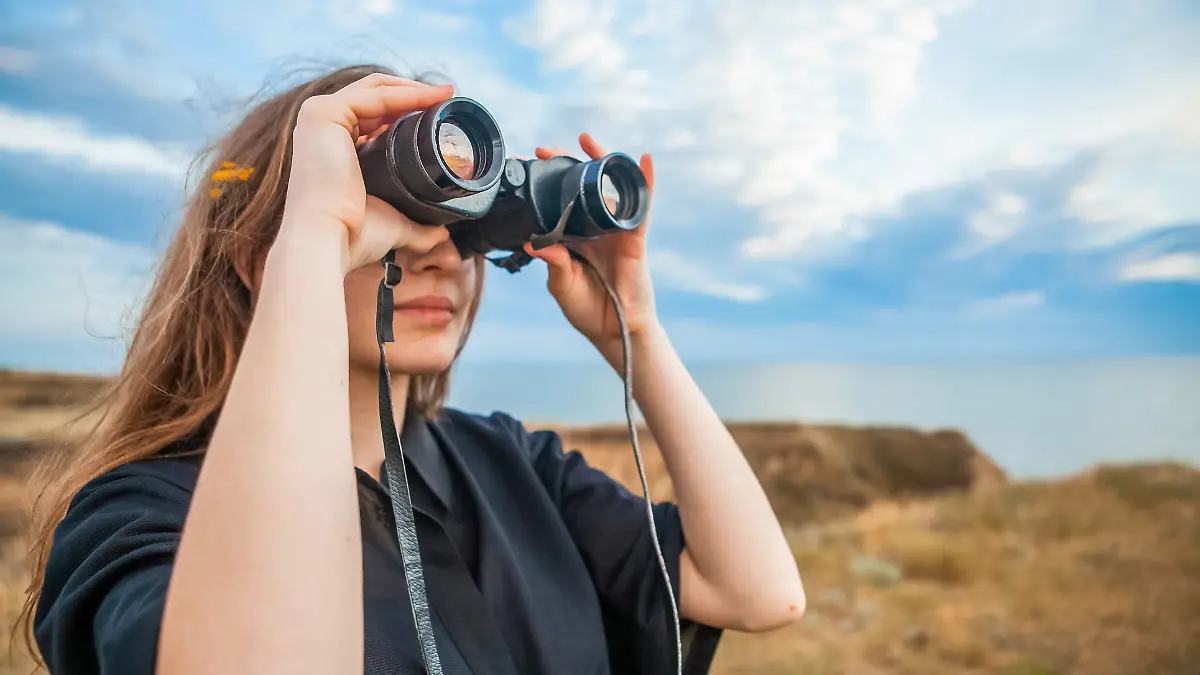 Frau schaut durch Fernglas