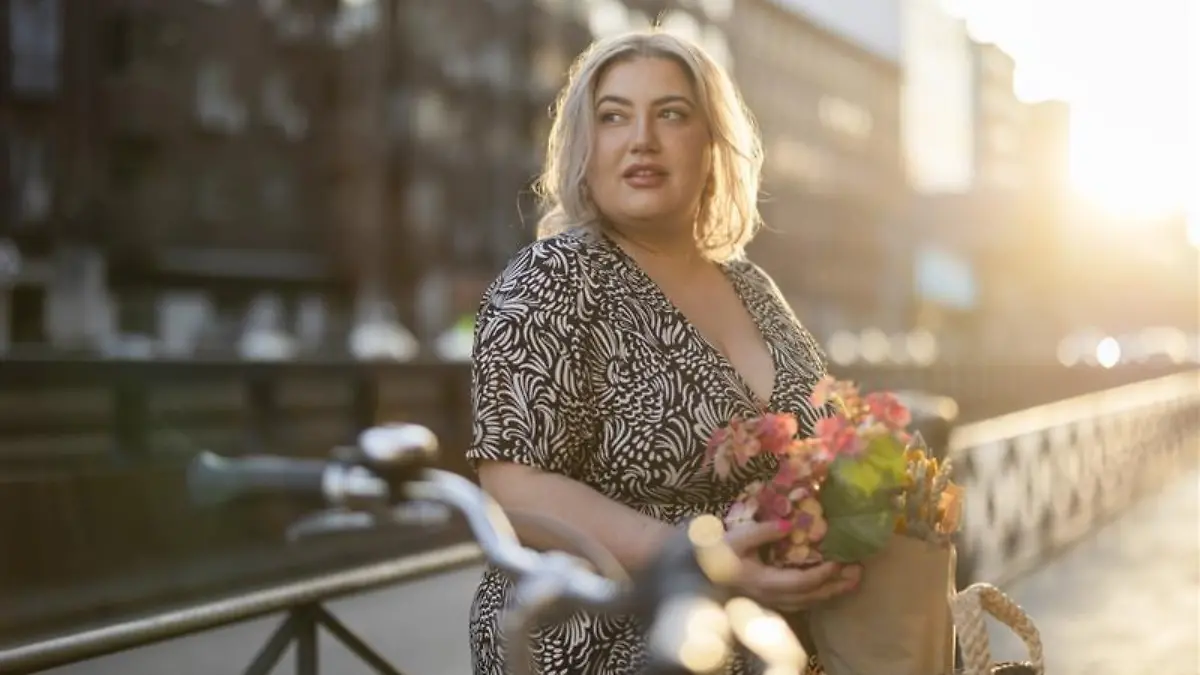 Blonde Frau steht vor einem Fahrrad.